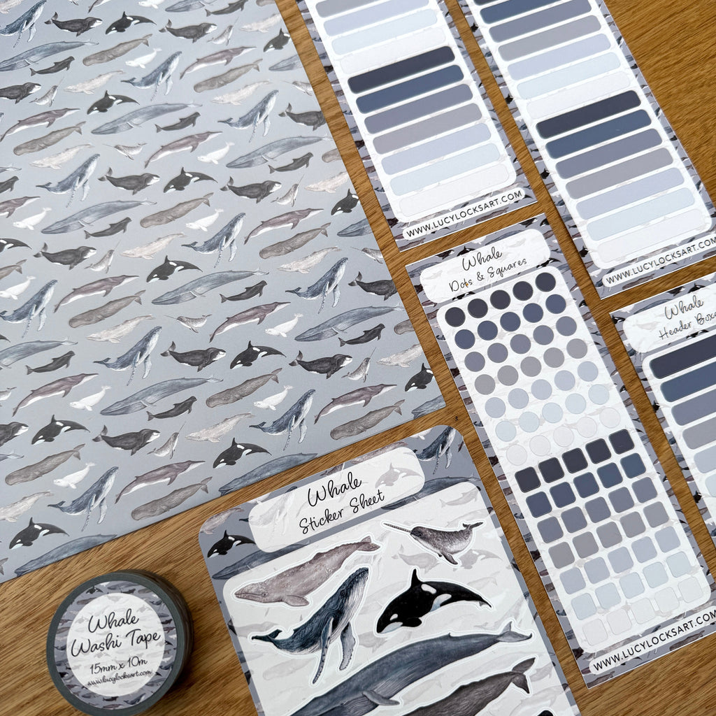 Collection of whale-themed journal stationery items including stickers and tape on a wooden surface.