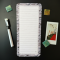 Long, narrow magnetic list with lined pages on a megnetic surface with decorative items.