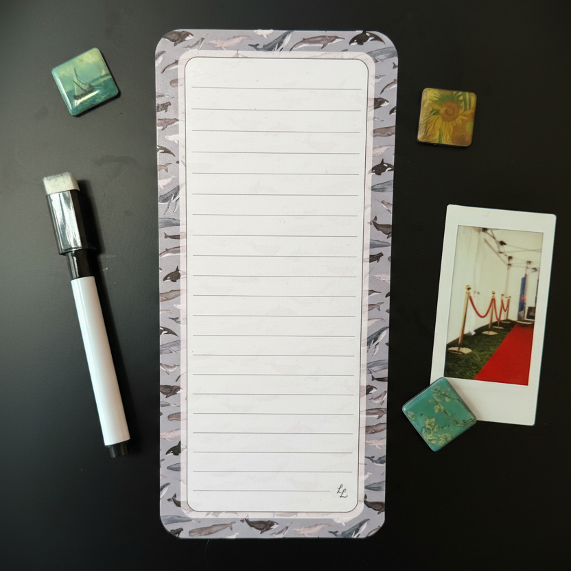 Long, narrow magnetic list with lined pages on a megnetic surface with decorative items.