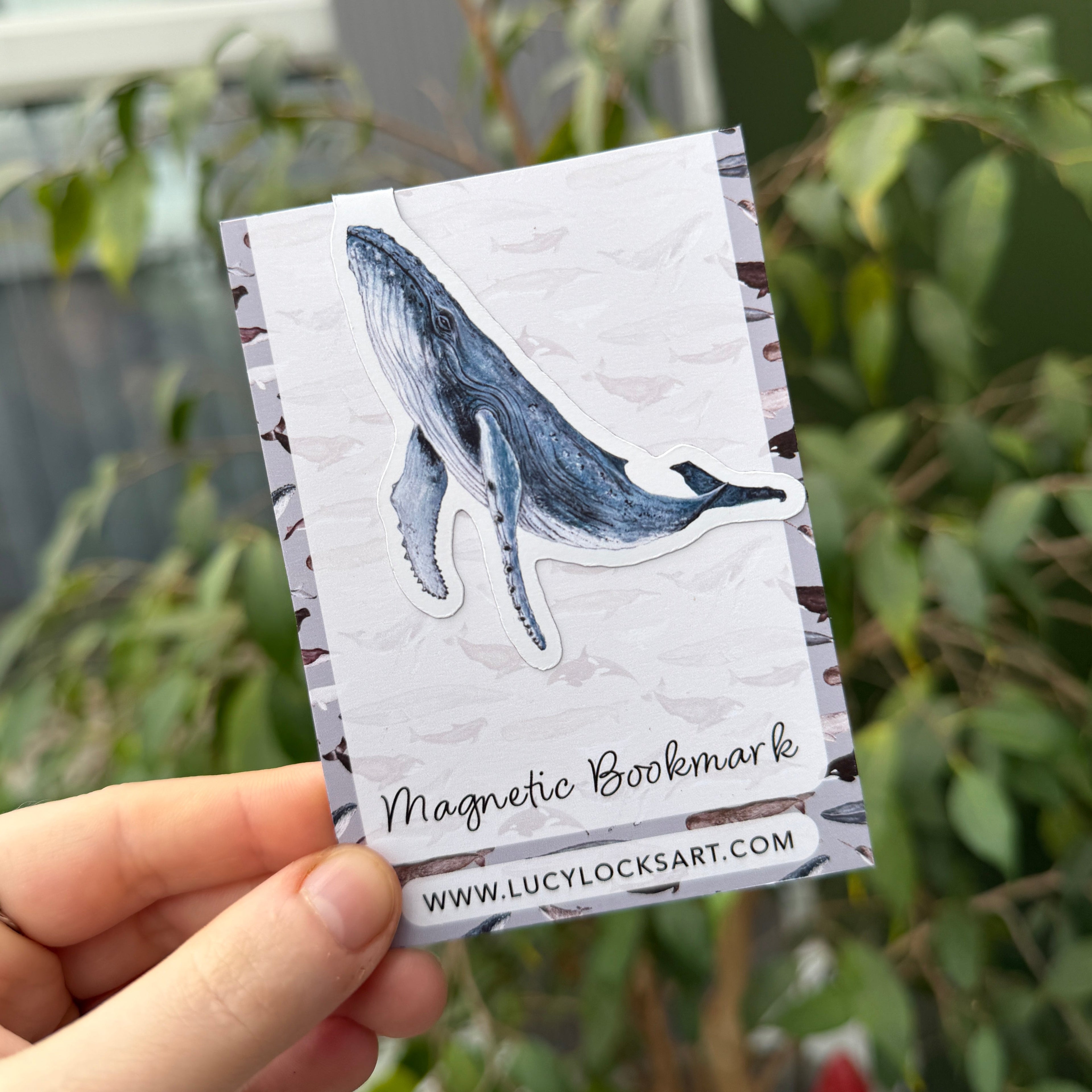 Hand holding a whale magnetic bookmark