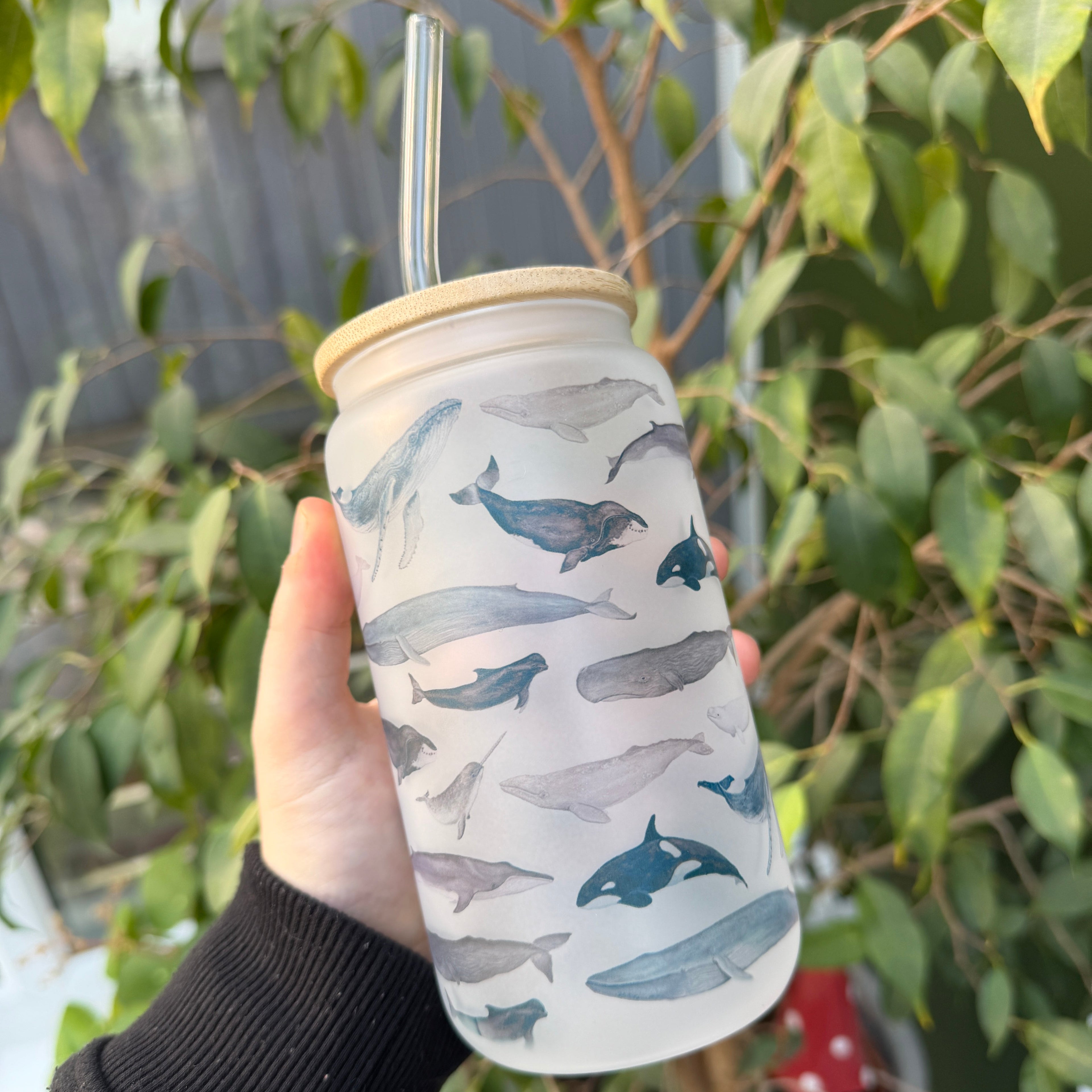 Hand holding a tumbler with whale design outdoors